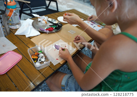 Mother and her daughter paint Halloween cookies Mother and her daughter paint Halloween cookies 128218775