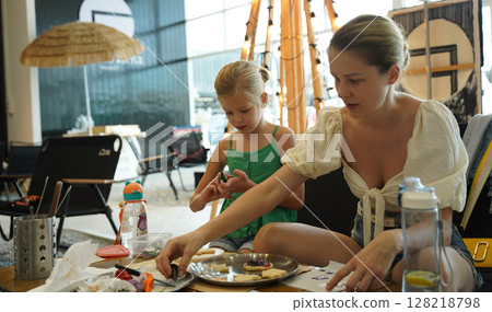 Mother and her daughter paint Halloween cookies Mother and her daughter paint Halloween cookies 128218798