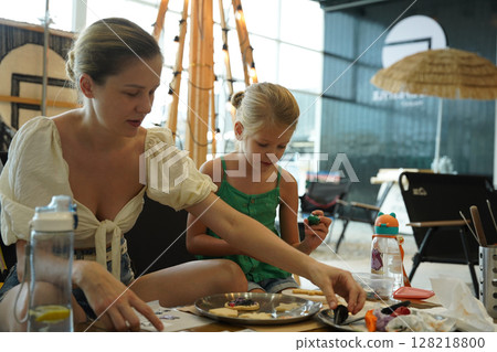 Mother and her daughter paint Halloween cookies Mother and her daughter paint Halloween cookies 128218800