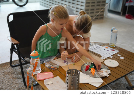 Mother and her daughter paint Halloween cookies  128218805