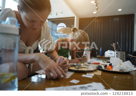 Mother and her daughter paint Halloween cookies Mother and her daughter paint Halloween cookies 128218813