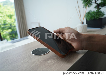 Charging mobile phone battery with wireless charging device in the table 128218830