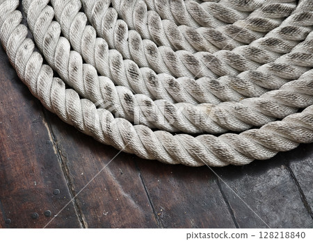 A sailor ropes is laying spread out on a wooden floor A sailor ropes is laying spread out on a wooden floor 128218840