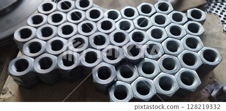 Flanged steel hex nuts stacked on the table. Tool. Steel Screw Nuts. Hex nuts in a pattern. Mechanical engineering. Is used in such fields as mechanical engineering, oil and gas, metallurgy, chemical, 128219332