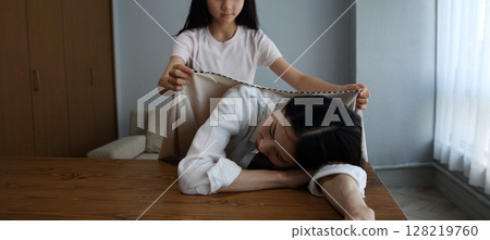 An image of a daughter covering her mother who has fallen asleep due to fatigue 128219760