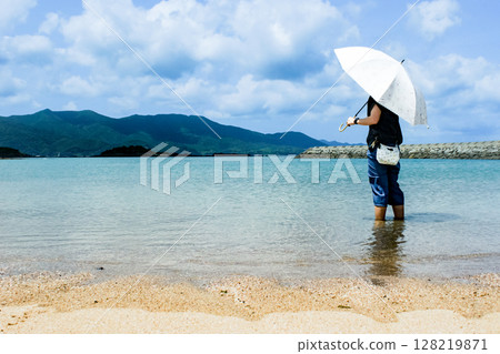 <Material> A woman alone at the sea in summer looking at the clouds in the sky 128219871