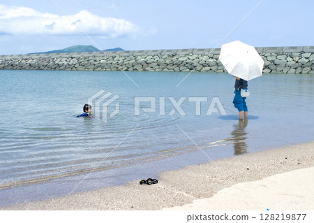 <Material> A mother watches her children play in the summer sea 128219877