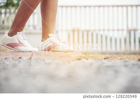 Sport sneakers footwear young woman knelt down do up shoelaces. Ready running shoes in sport exercise jogging person. Close up hands tie up runner shoelaces in fitness gym healthy person lifestyle. 128220349