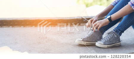 sneaker shoes young woman traveler sit down on summer park. Focus on sneaker shoes and jeans on pathway in forest park. active activity vacation on hike mountain walking way. Young traveler concept sneaker shoes young woman traveler sit down on summer park. Focus on sneaker shoes and jeans on pathway in forest park. active activity vacation on hike mountain walking way. Young traveler concept 128220354