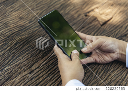 Close up woman hands using smartphone online video call texting message. Female hand touch empty screen cellphone smart tablet on hands using mobile app home office. Asian woman sitting wooden table Close up woman hands using smartphone online video call texting message. Female hand touch empty screen cellphone smart tablet on hands using mobile app home office. Asian woman sitting wooden table 128220363