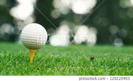Golf ball on tee in green golf field with recreation sport training course. Tee and ball Sports Equipment in Golf Tournament. 128220403