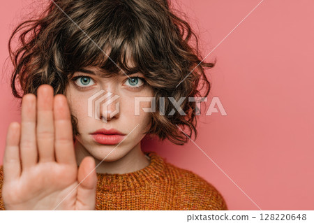 Portrait of Woman Showing Stop Gesture with Hand Against Pink Background 128220648