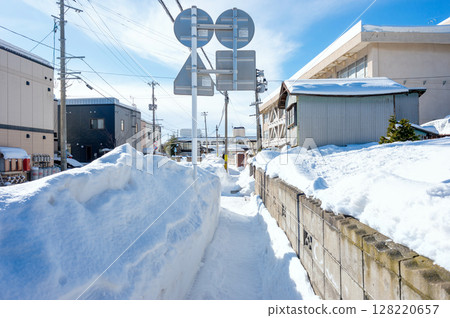 Life in a snowy country: A long-awaited sunny day in the middle of heavy snowfall, the sidewalk in front of the elementary school Life in a snowy country: A long-awaited sunny day in the middle of heavy snowfall, the sidewalk in front of the elementary school 128220657