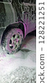 Car wash close-up with white and vibrant pink foam covering the vehicle. Cleaning process. Self-service station, no people. Perfect for auto care, maintenance, and service concepts. Advertising. 128221251
