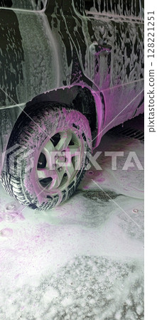 Car wash close-up with white and vibrant pink foam covering the vehicle. Cleaning process. Self-service station, no people. Perfect for auto care, maintenance, and service concepts. Advertising. 128221251
