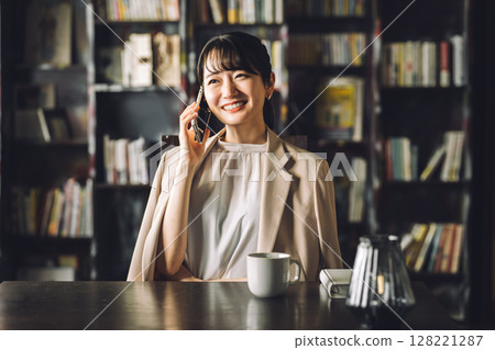 Asian woman using tablet PC while talking on the phone in study, library, businesswoman Asian woman using tablet PC while talking on the phone in study, library, businesswoman 128221287