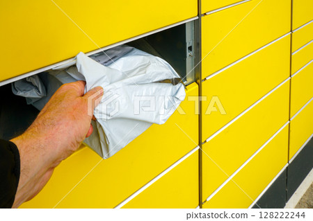 Man Retrieves Parcel from Yellow Automated Locker Using a Self-Service Pickup System Man Retrieves Parcel from Yellow Automated Locker Using a Self-Service Pickup System 128222244