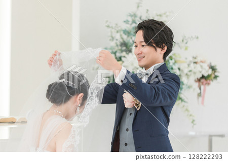 Groom lifting the bride's veil at a wedding ceremony (veil up) Groom lifting the bride's veil at a wedding ceremony (veil up) 128222293