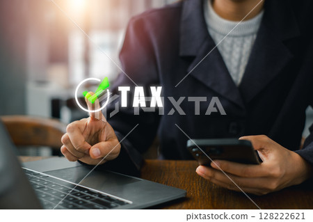 A business professional using a laptop and smartphone to manage taxes, highlighting modern financial technology. A business professional using a laptop and smartphone to manage taxes, highlighting modern financial technology. 128222621