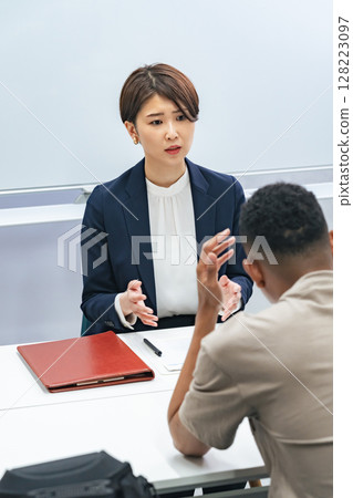 A Japanese female staff member interviewing a troubled black man A Japanese female staff member interviewing a troubled black man 128223097