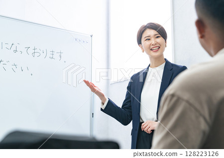 A female teacher teaches business terms to a black man at a Japanese language school 128223126