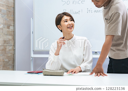 A black man and a Japanese woman having a conversation in a classroom 128223136