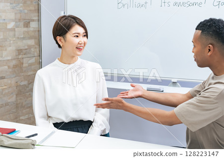 A black man and a Japanese woman having a conversation in a classroom A black man and a Japanese woman having a conversation in a classroom 128223147