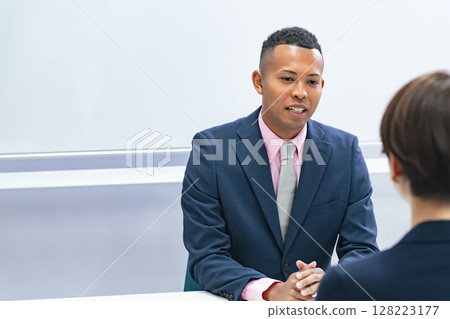 A Japanese female staff member interviewing a black male businessman 128223177