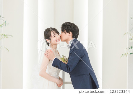 Bride and groom kissing on the cheek at wedding ceremony Bride and groom kissing on the cheek at wedding ceremony 128223344