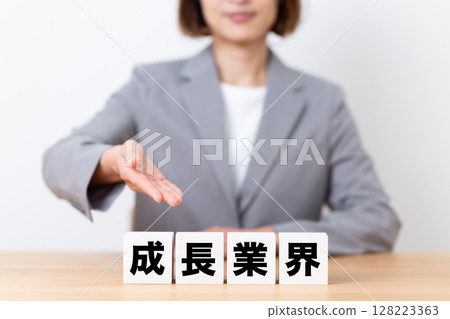 一位中年女商界女性穿著西裝，手裡拿著一塊正在成長的行業 128223363