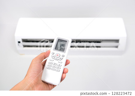 Man's hand using remote control open The air conditioner is cooled to 25 degrees Celsius in his bedroom. Health concepts and energy savings Man's hand using remote control open The air conditioner is cooled to 25 degrees Celsius in his bedroom. Health concepts and energy savings 128223472
