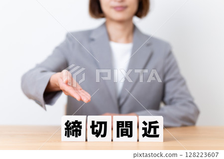 A middle-aged business woman wearing a suit and a block with a deadline approaching A middle-aged business woman wearing a suit and a block with a deadline approaching 128223607