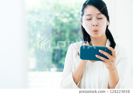 Businesswoman watching a video on her smartphone Businesswoman watching a video on her smartphone 128223638