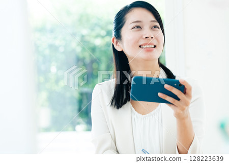 Businesswoman watching a video on her smartphone 128223639