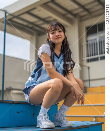 Female student in gym clothes sitting in gym 128223716