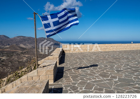 Greek flag waving on a viewpoint overlooking mountains and sea in crete, greece 128223726