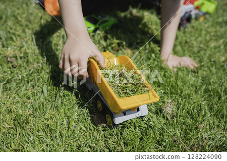 A child plays with toy cars on the lawn in the sunny day 128224090