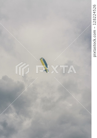 Paraglider soaring high under dramatic cloudy sky in mountain region. High quality photo 128224526