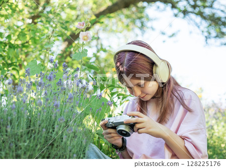 Young photographer capturing lavender field beauty with headphones and camera 128225176