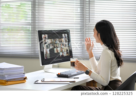 Businesswoman joins a virtual meeting on her desktop computer in a bright office 128225325