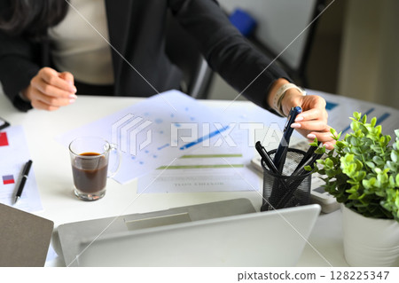 Female financial expert evaluating documents and preparing budget data at desk Female financial expert evaluating documents and preparing budget data at desk 128225347