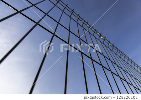 a thin metal lattice fence against a sky background, a small thin fence dividing the territory 128226103