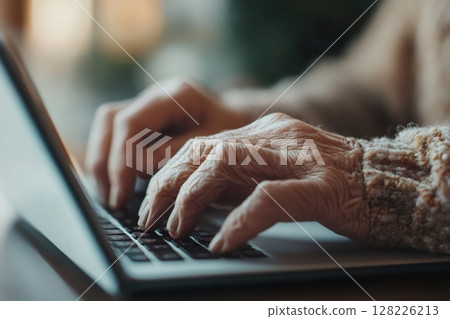 Elderly person using laptop: detail of wrinkled hands typing on keyboard 128226213