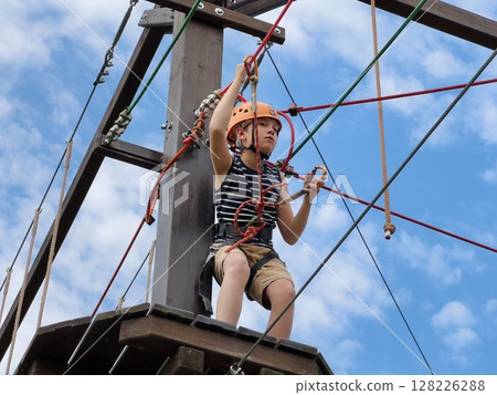 a teenage boy in outdoor rope park passing obstacle course. Active summer holidays 128226288