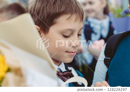 A 10-year-old boy carries a bouquet of flowers before school on September 1st, dressed in formal attire with a backpack. A 10-year-old boy carries a bouquet of flowers before school on September 1st, dressed in formal attire with a backpack. 128226297