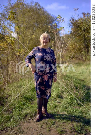 a   portrait of an elderly woman with gray hair in a dress  in the autumn forest 128226388