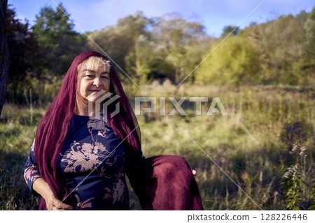 portrait of an elderly woman with gray hair in a dress and shawl in the autumn forest portrait of an elderly woman with gray hair in a dress and shawl in the autumn forest 128226446