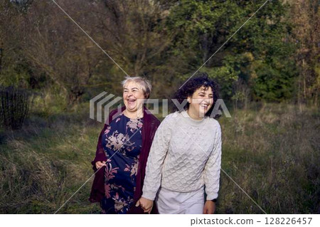 middle-aged daughter and elderly mother together on a walk in the autumn forest 128226457