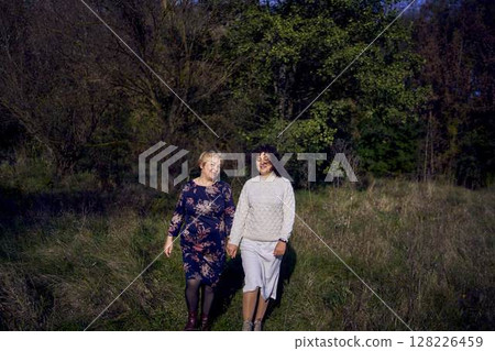 middle-aged daughter and elderly mother together on a walk in the autumn forest 128226459