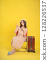 Traveler Sitting on a Chair with Luggage Against a Yellow Background 128226537